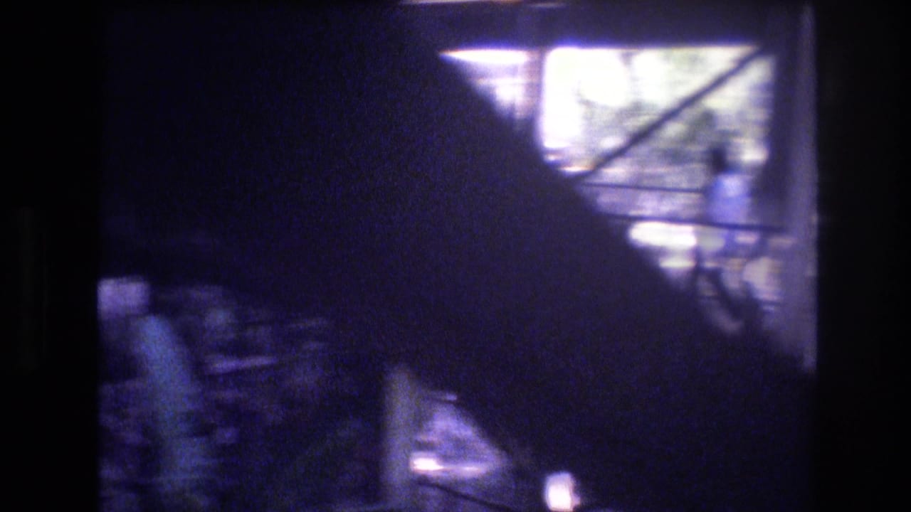 1977 Honolulu 8mm frame looking through a dark window area toward bright reflected glass and indistinct exterior forms.