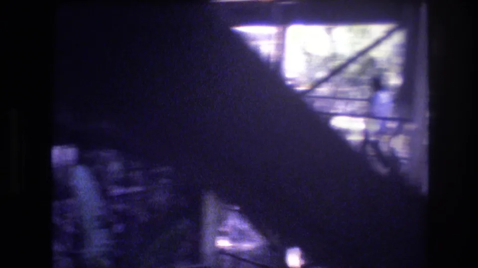 1977 Honolulu 8mm frame looking through a dark window area toward bright reflected glass and indistinct exterior forms.