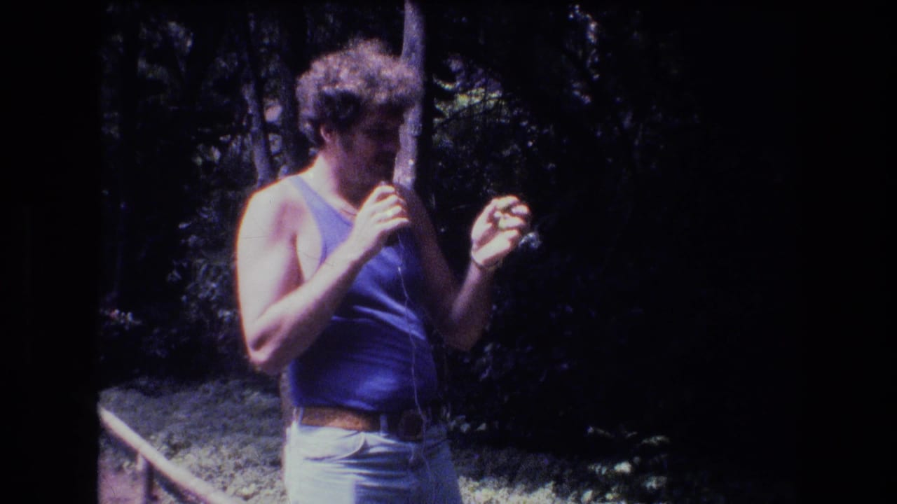 Man looks down while holding a small object in one hand.