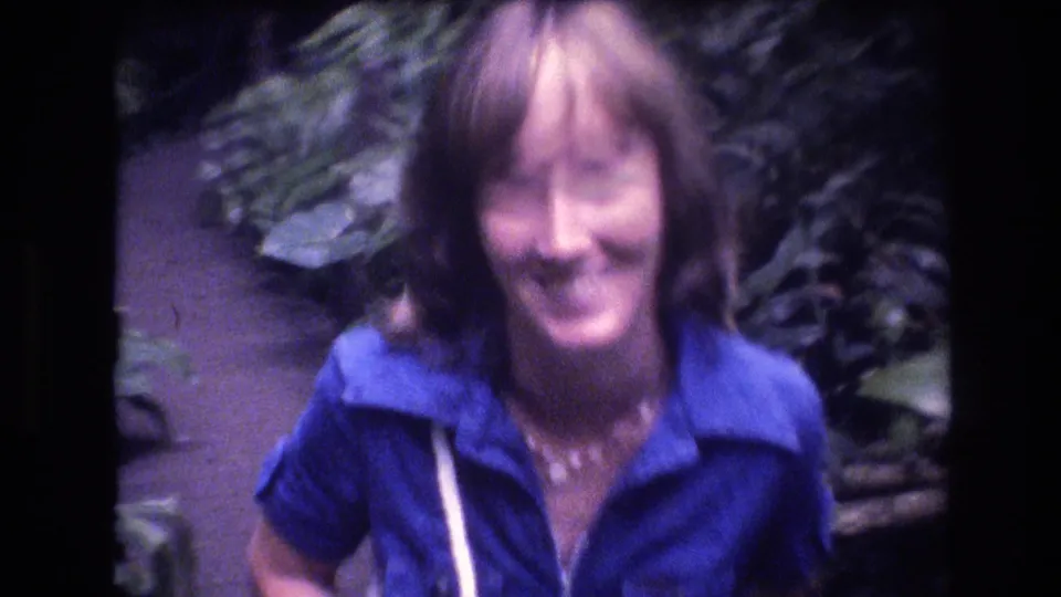 A closer 8mm frame shows the smiling woman facing the camera on a tropical Oahu path, with soft focus and dense greenery around her.