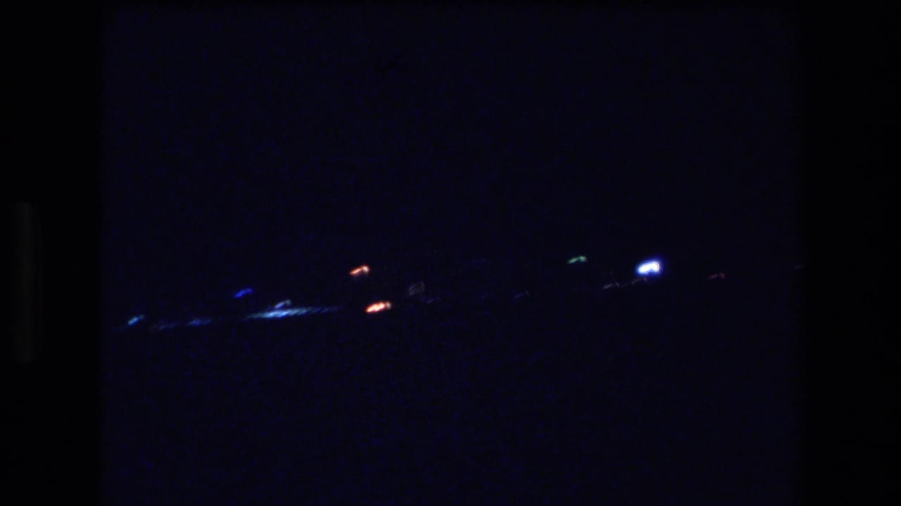 1977 Honolulu or Oahu 8mm frame showing scattered distant shoreline lights against a dark blue-black night view.