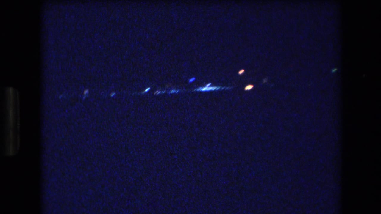 Blue-black night view with small scattered lights near the horizon.