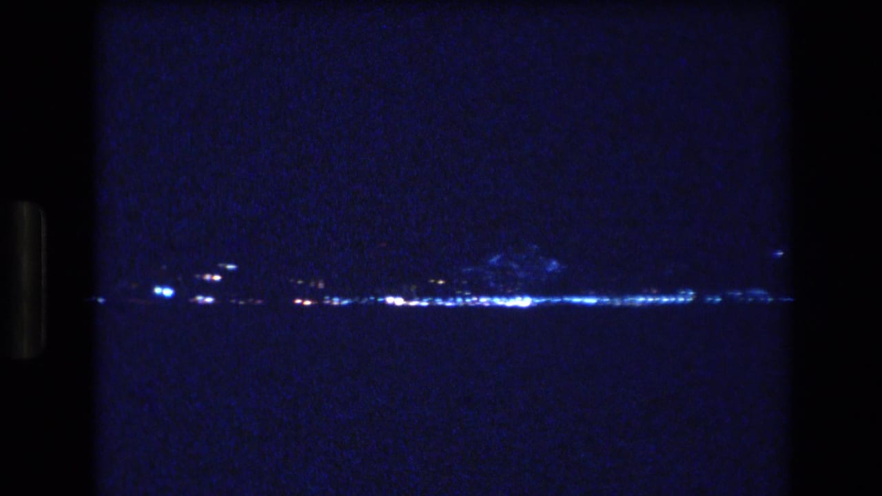 Small clusters of bright lights appear across a dark shoreline at night.