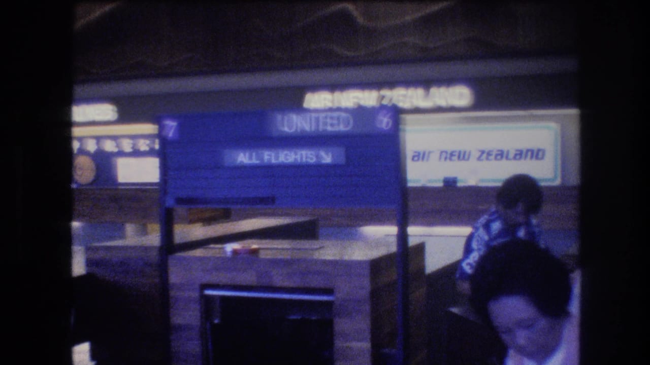 Airport terminal signs include United and Air New Zealand branding with passengers in the foreground.