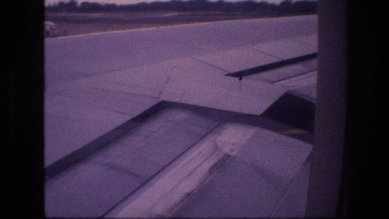 Aircraft wing and flap section visible beyond a dark window frame.
