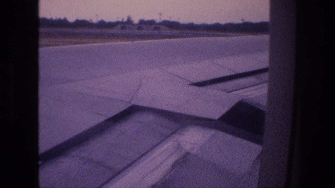 1977 Honolulu, Oahu frame with the aircraft wing filling the lower view as the runway and low horizon pass outside the cabin window.