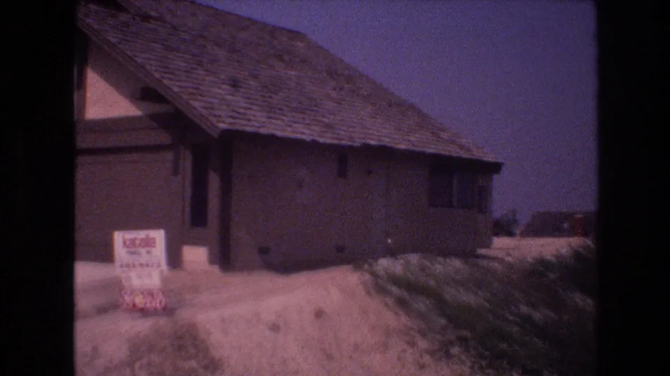 1977 Honolulu Oahu 8mm frame showing a private suburban house near roadside vegetation with a visible sold sign posted in front.