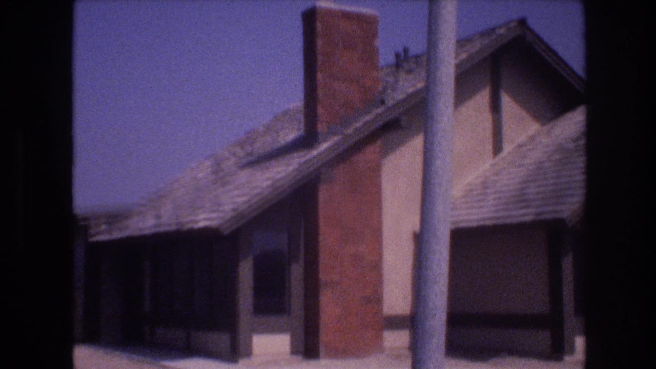 Residential house roofline with brick chimney, vertical pole, and dark frame edge.