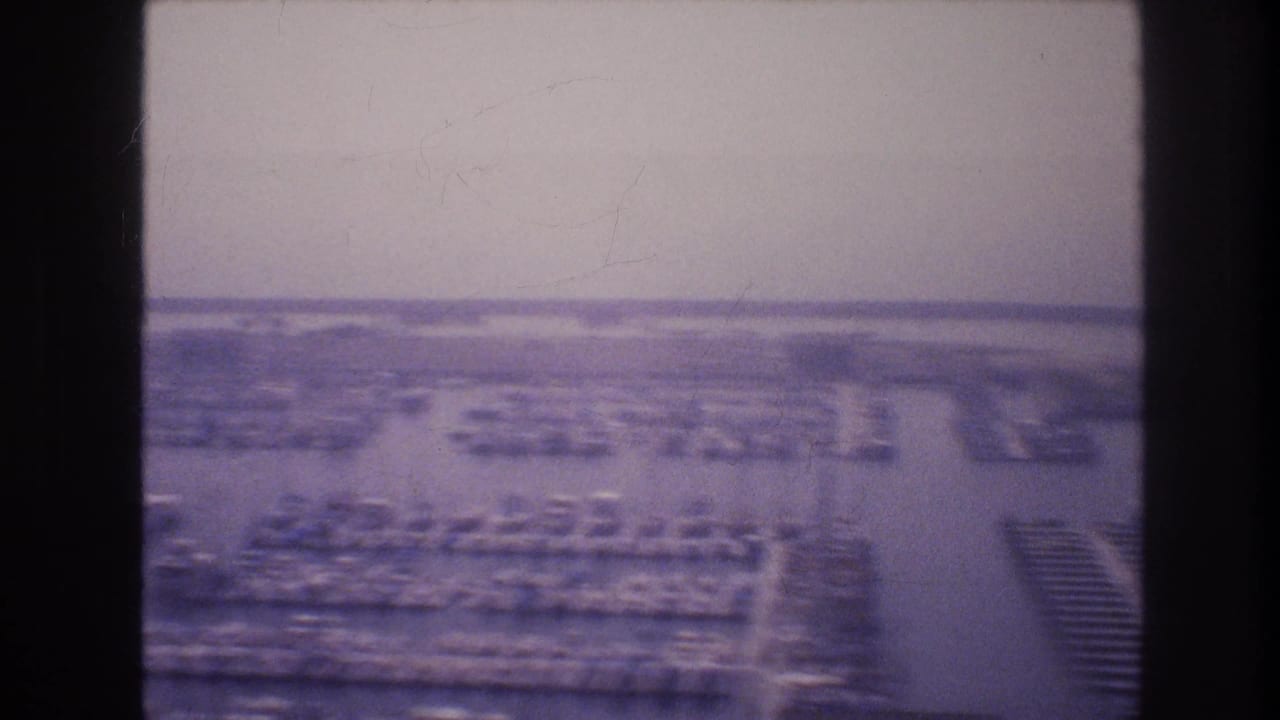 Soft distant city view with parking areas and buildings seen through dark film-frame borders.