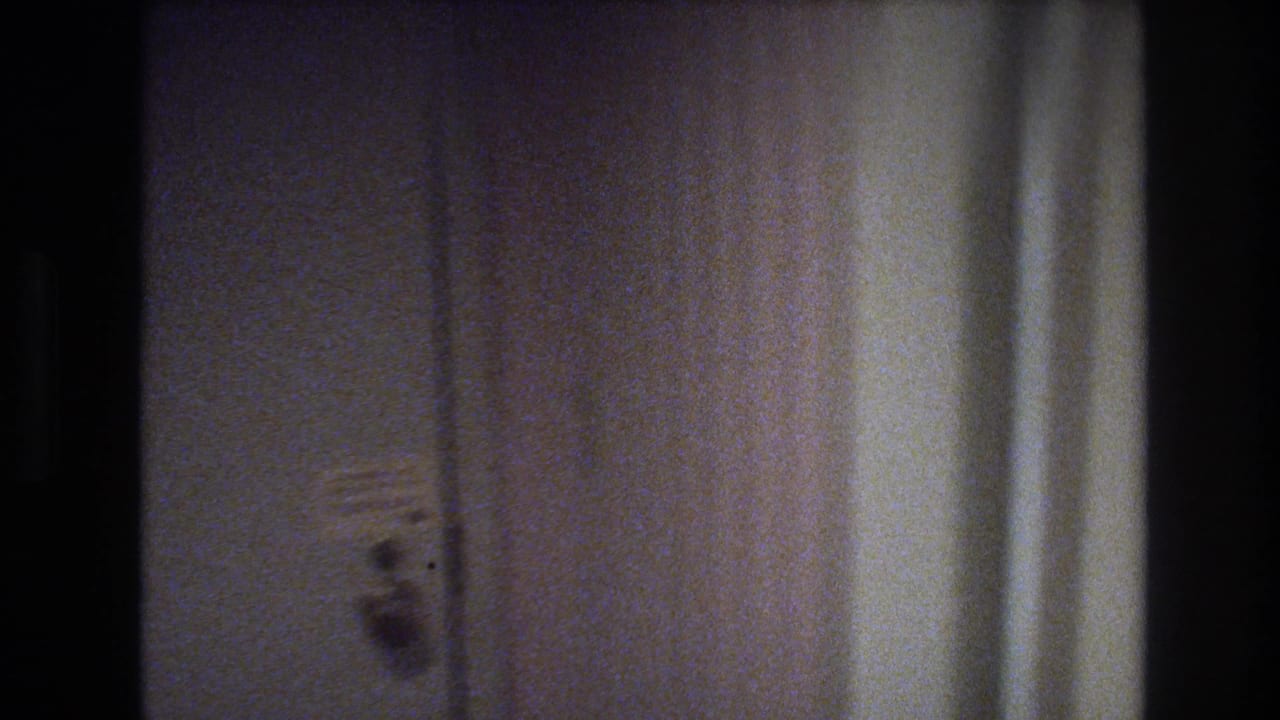 Interior room walls with a small wall-mounted item and a curtain visible at the right edge; no people visible.