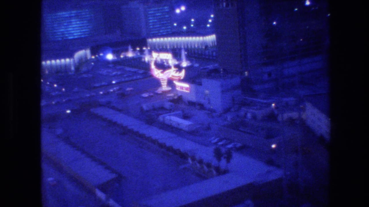 Handheld 8mm view from an upper floor looking down at Las Vegas neon signage and casino buildings at night, circa 1977.