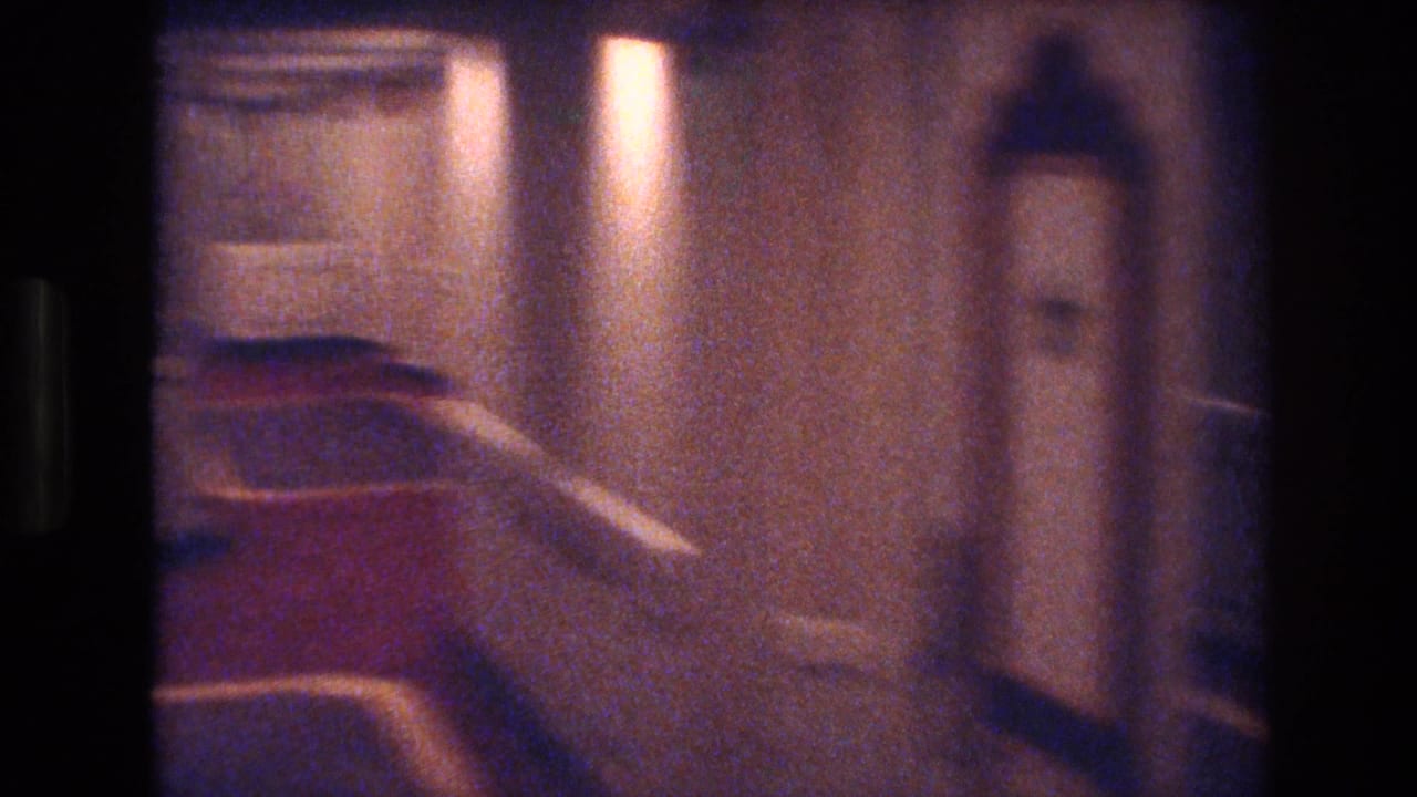 Handheld 8mm travel footage, c. 1977, showing a Las Vegas hotel corridor with red carpet, arched doorways, and warm overhead lighting.