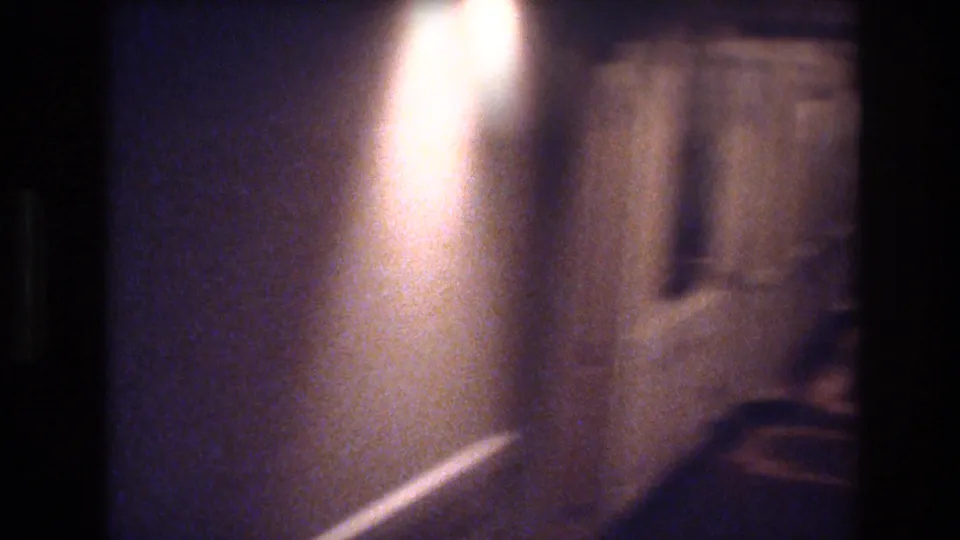 Dark handheld 8mm corridor shot with severe underexposure and motion blur, c. 1977 Las Vegas hotel interior.