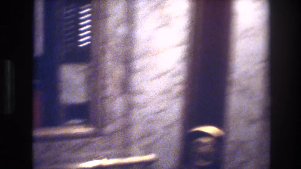 Final frame of 1970s Las Vegas hotel sequence shot on 8mm; camera pans to a reflective surface, producing heavy motion blur and light reflections across the frame.