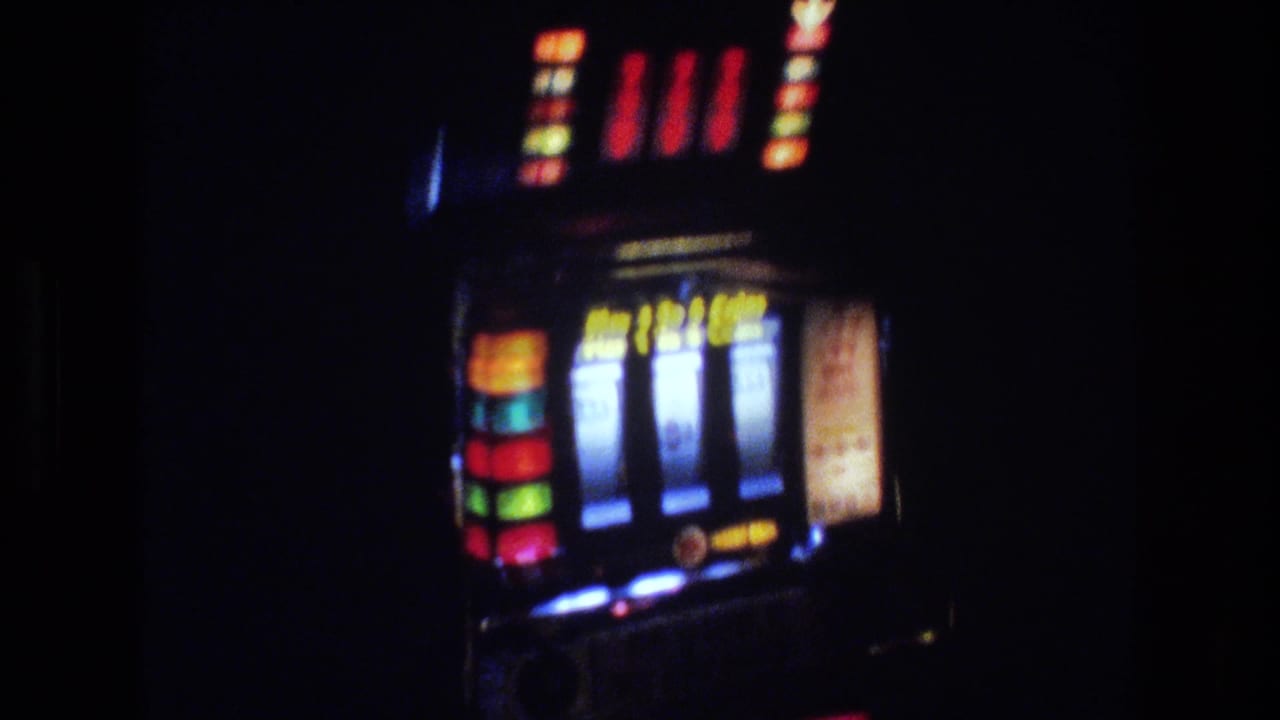 Slot machine with three visible reels and multi-color backlit indicators in a dimly lit casino environment.