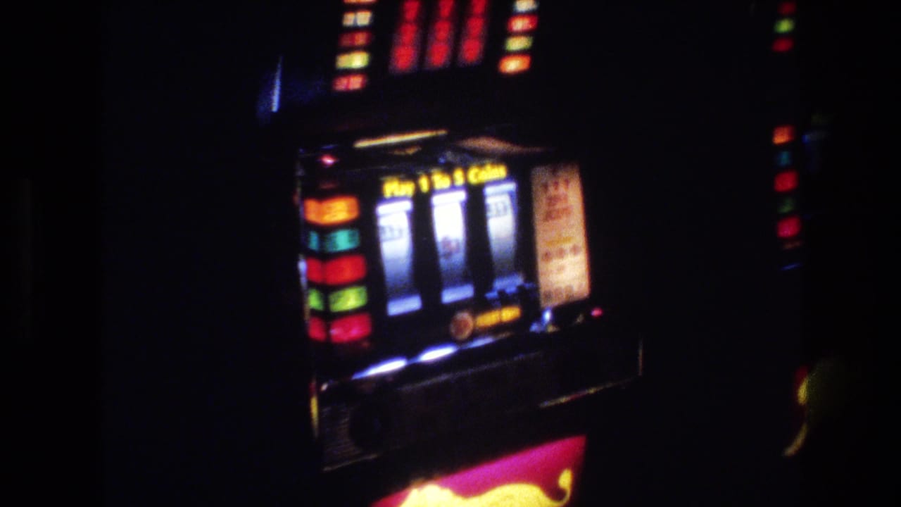 Slot machine with illuminated colored reels, a coin-play text panel, and a colorful decorative graphic on the lower cabinet face.