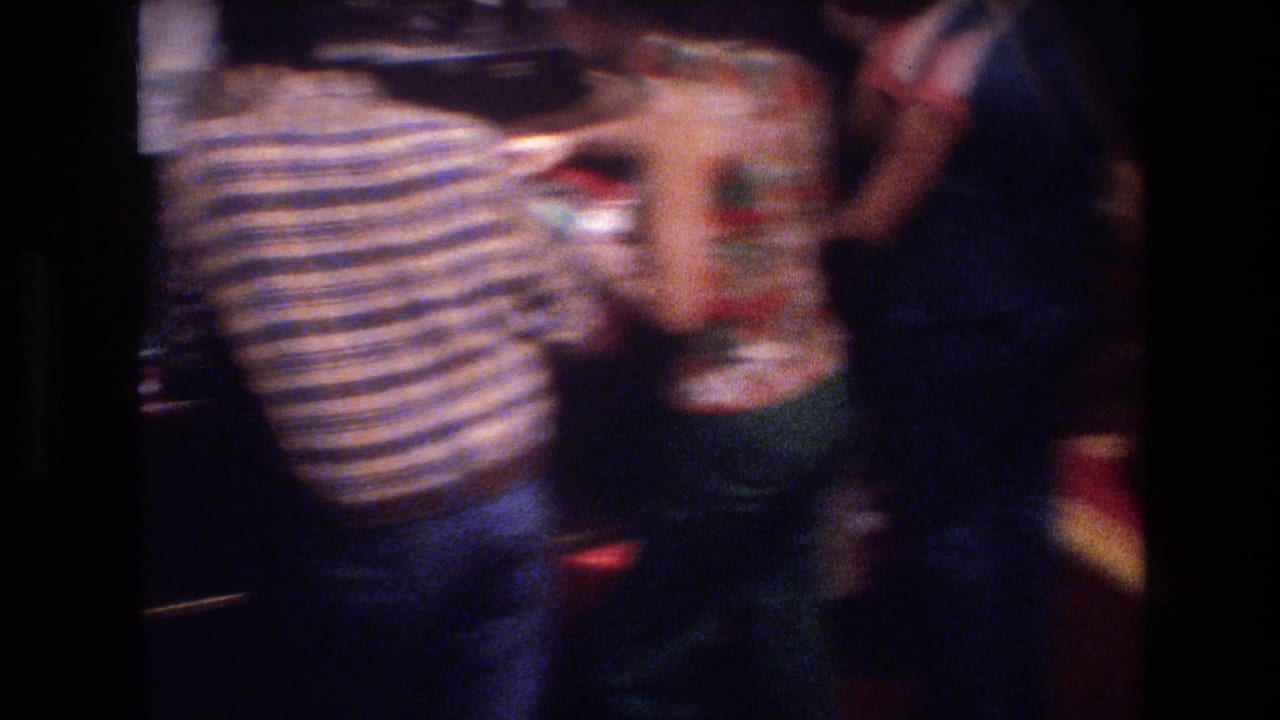 Super 8 close shot of casino patrons at a Las Vegas gaming table circa 1977, dominated by a figure in a blue-and-white striped shirt, with significant motion blur.