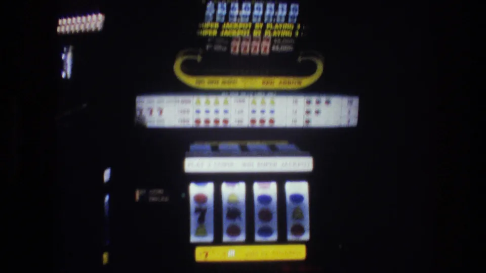 "RED ARROW" branded slot machine showing reels with a seven symbol, lit payout table, and "SUPER JACKPOT" text, filmed in a Las Vegas casino circa 1977 on 8mm film.