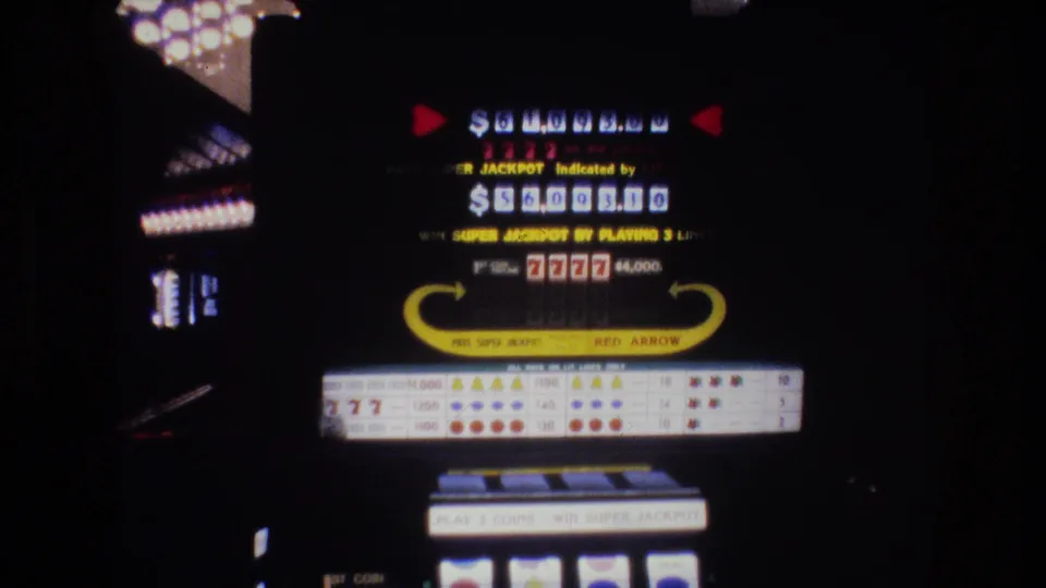 8mm film of a 1977 Las Vegas slot machine showing a large jackpot dollar display, "SUPER JACKPOT Indicated by" text, "7777" symbols, "RED ARROW" branding, and payout table.