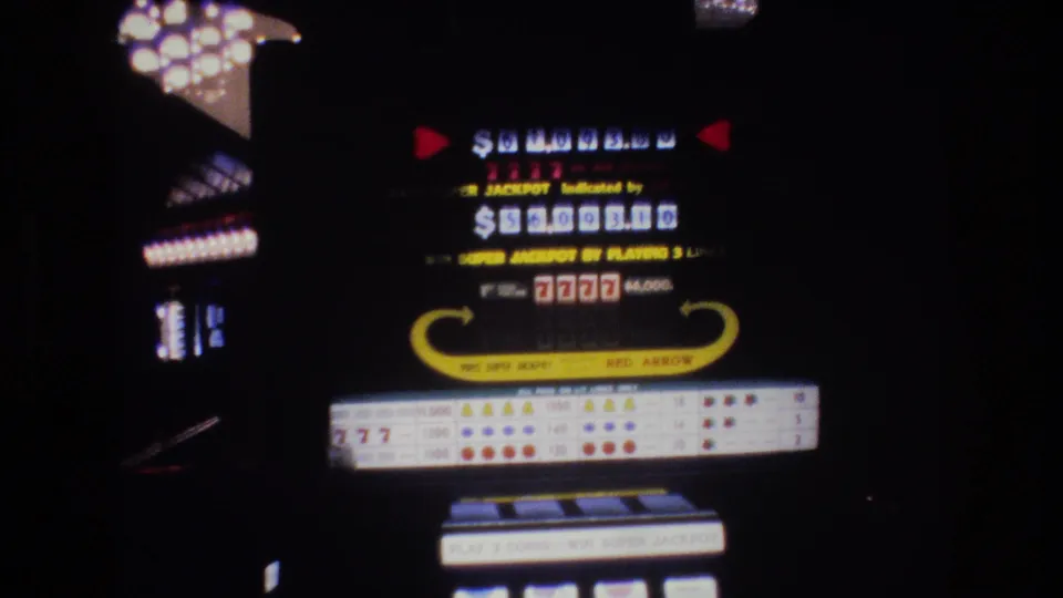 1977 Las Vegas 8mm home movie of a "RED ARROW" slot machine showing jackpot dollar display, "7777" symbols, payout table, and reels in a darkened casino interior.