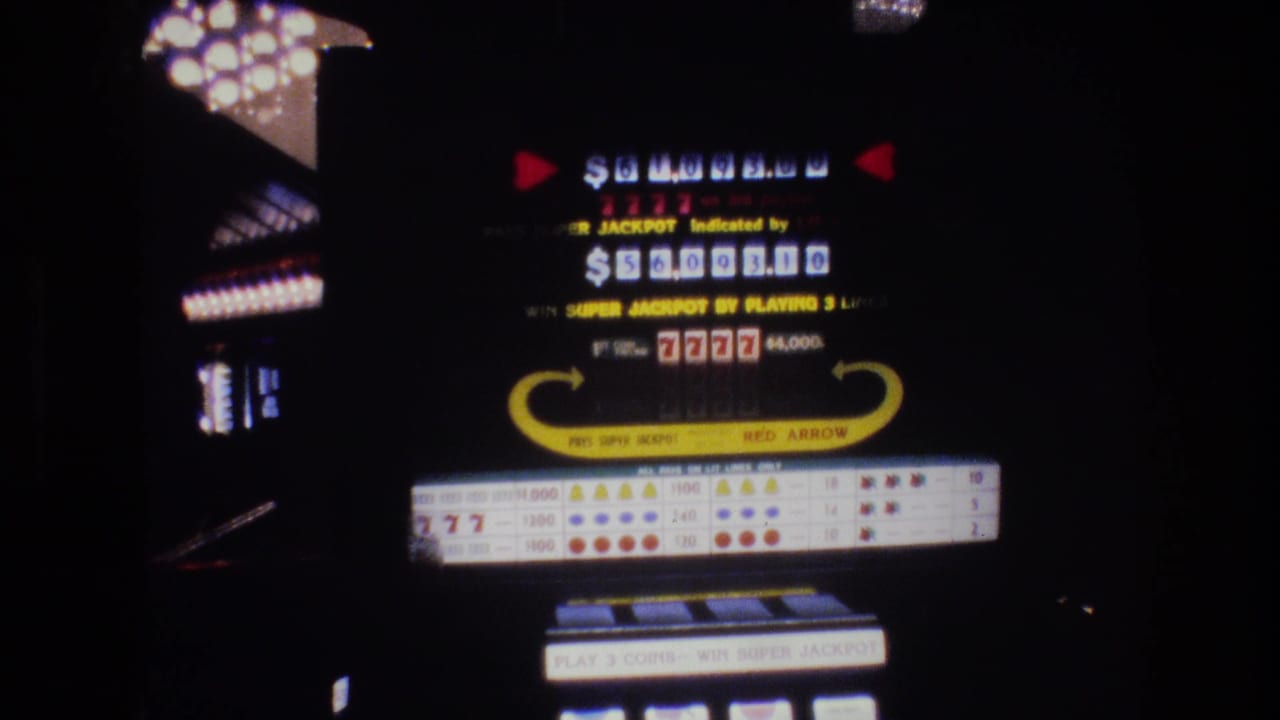 Illuminated slot machine display panel in a dark casino showing a Super Jackpot dollar amount and 7777 winning combination.