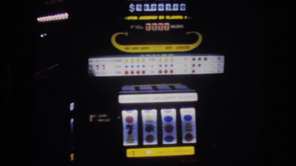 Close-up of a Las Vegas casino slot machine, circa 1977, showing jackpot display, 7777 indicator, and reel symbols in low casino light on 8mm film.