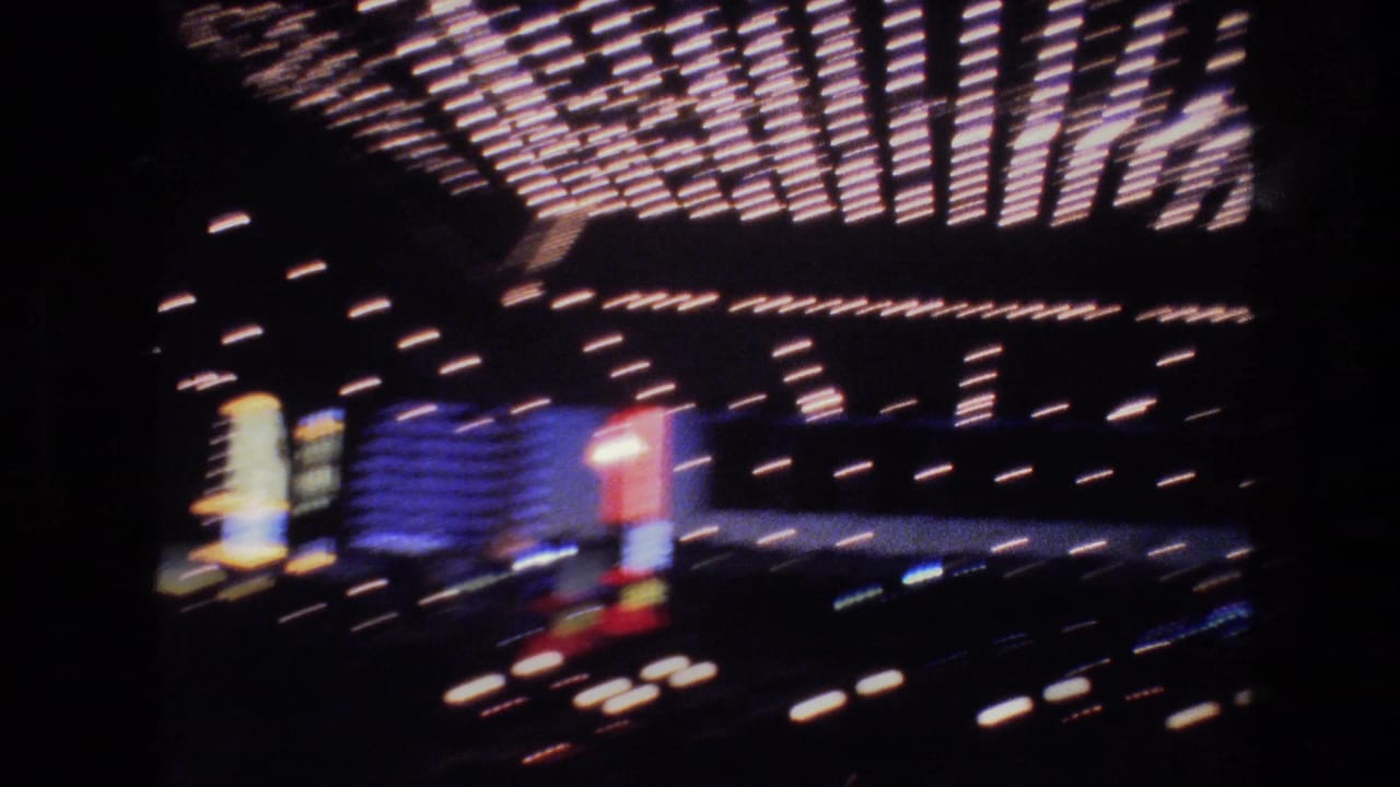 8mm footage of a Las Vegas hotel or casino marquee draped in rows of holiday lights, with multicolor neon signs in background, circa 1977