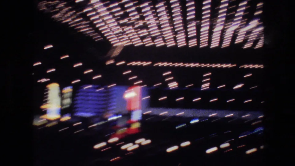 8mm footage of a Las Vegas hotel or casino marquee draped in rows of holiday lights, with multicolor neon signs in background, circa 1977