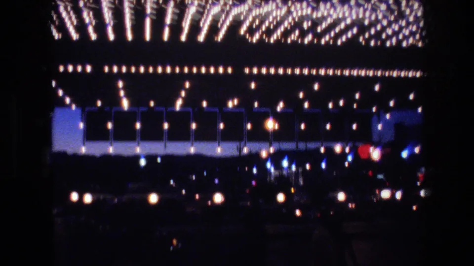 8mm frame of a massive Las Vegas commercial building facade covered in rows of incandescent holiday lights at twilight, circa 1977
