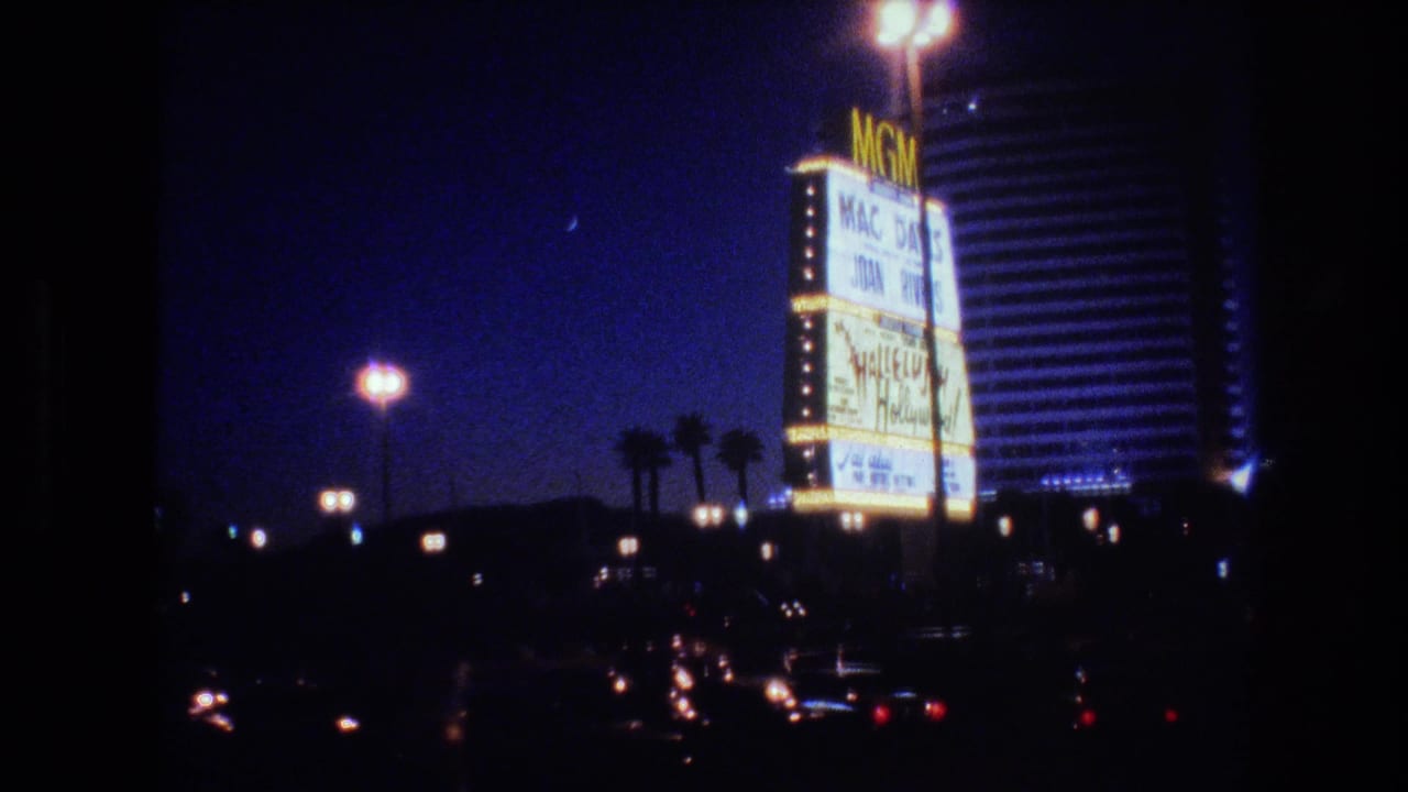 MGM Grand hotel tower at night with large illuminated yellow marquee sign, palm trees below, and a deep blue sky.