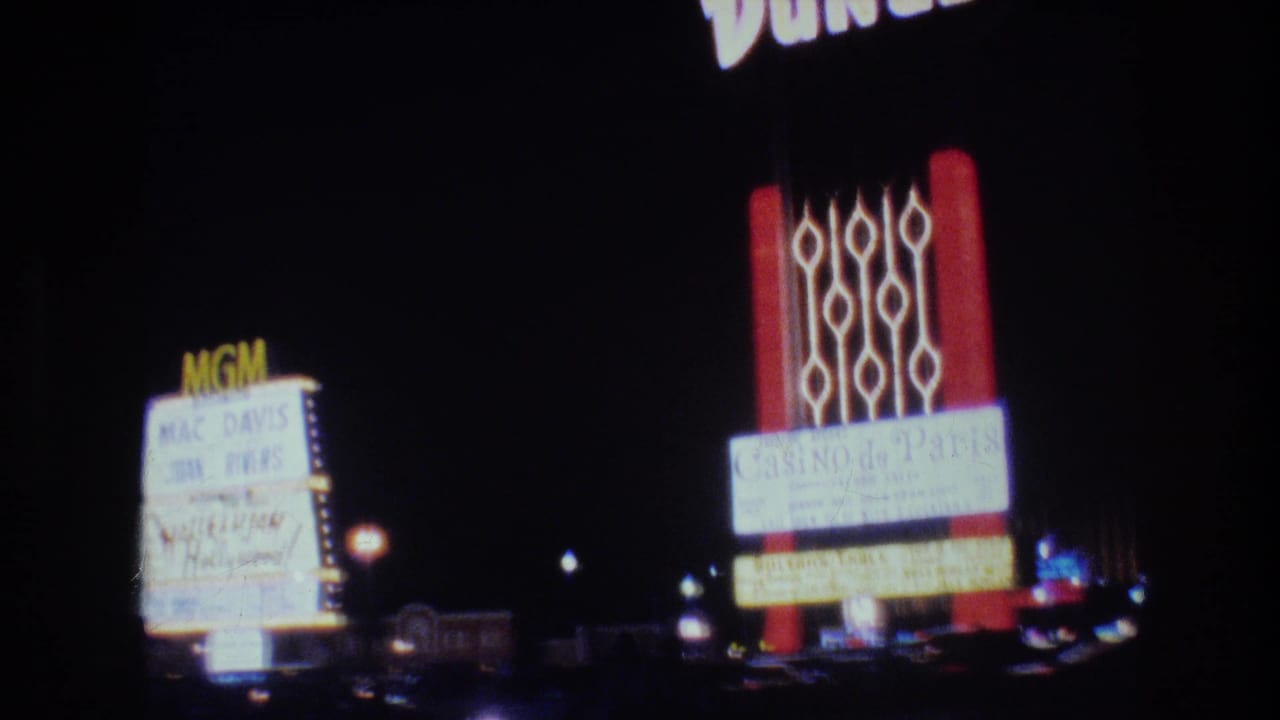 1977 Las Vegas frame with partial Dunes signage, MGM lettering, and a tall Casino de Paris marquee lit against a dark street.
