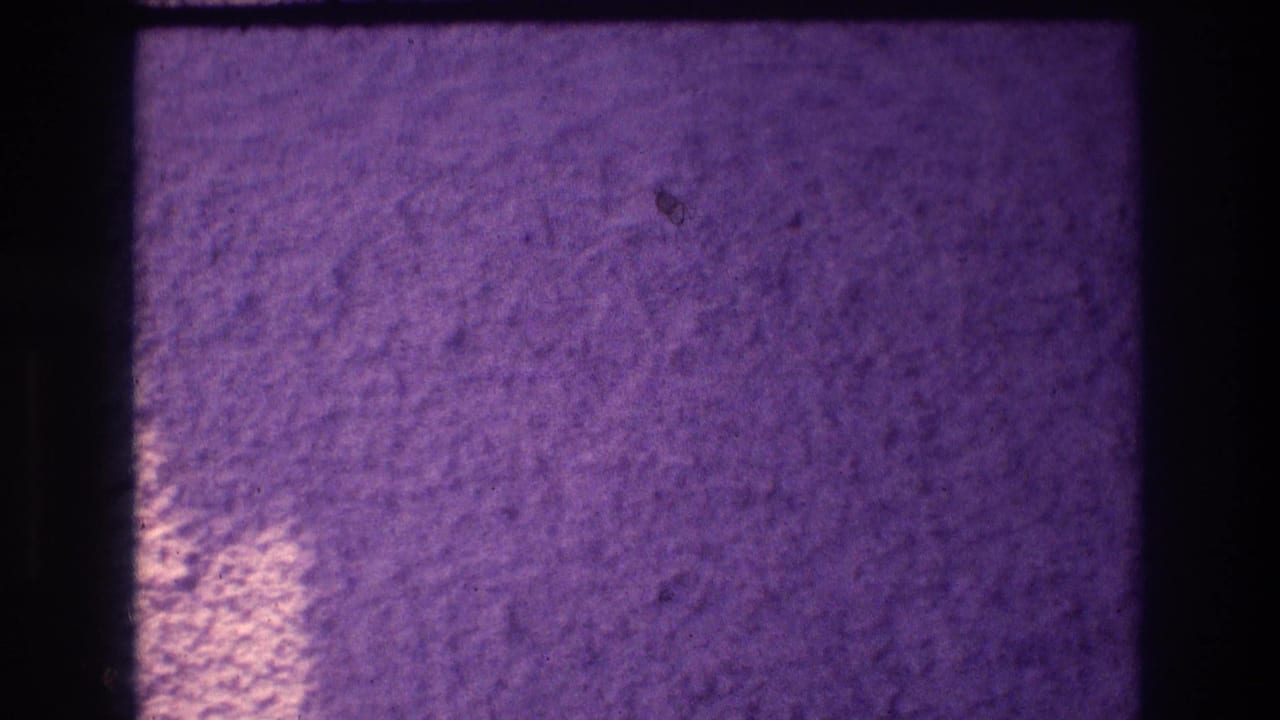 Rough stucco wall with a warm white light pool appearing at lower center against deep purple shadow.