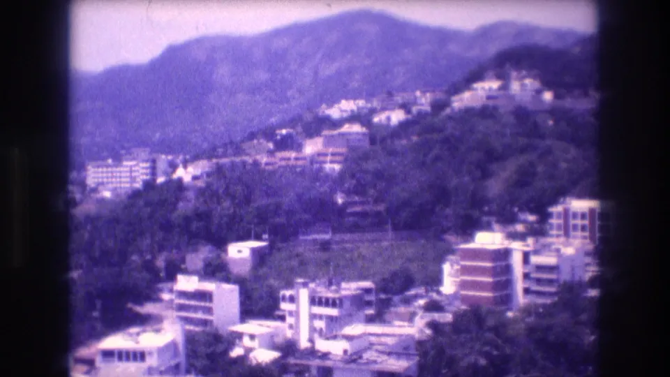 1982 8mm home-movie view from a hotel balcony showing hillside buildings, tropical vegetation, and mountain ridges, consistent with Acapulco, Mexico.