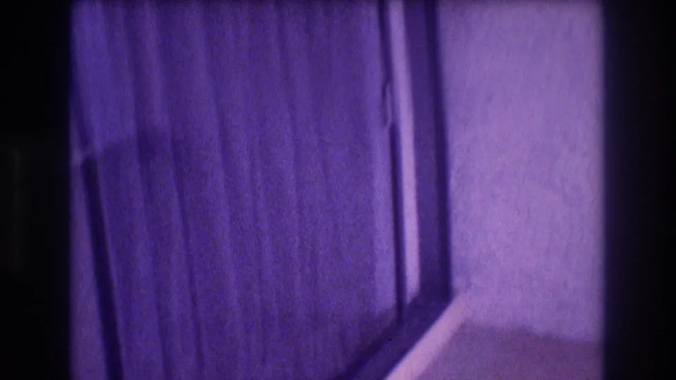 8mm close-up of a hotel room sliding glass door and curtains; heavy purple color shift consistent with aged 1980s film stock, Mexico.