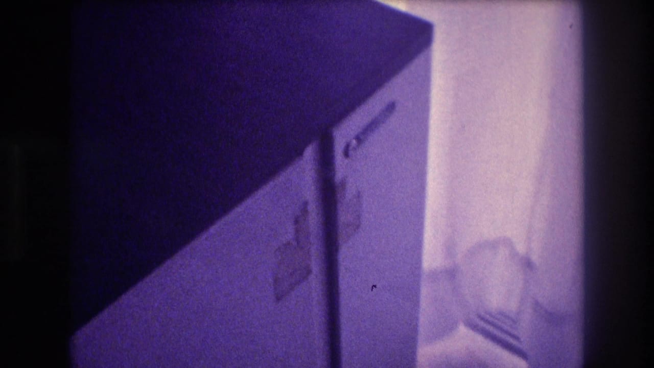 Compact white refrigerator door in mid-opening motion, dim indoor space, heavy purple Super 8 color shift, home movie footage circa 1982 Acapulco Mexico.