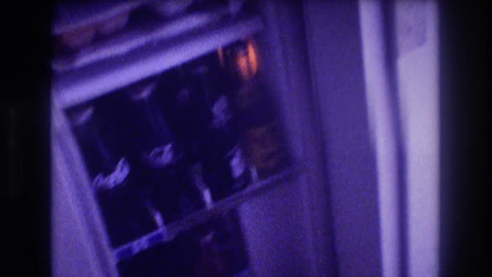 Interior of open compact refrigerator revealing multiple glass bottles on shelves and door rack, likely soft drinks, Super 8 home movie circa 1982 Acapulco Mexico.