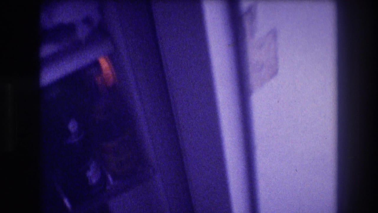 Blurred transitional shot of camera panning away from a dark refrigerator interior toward a white wall, with a warm-colored label visible.