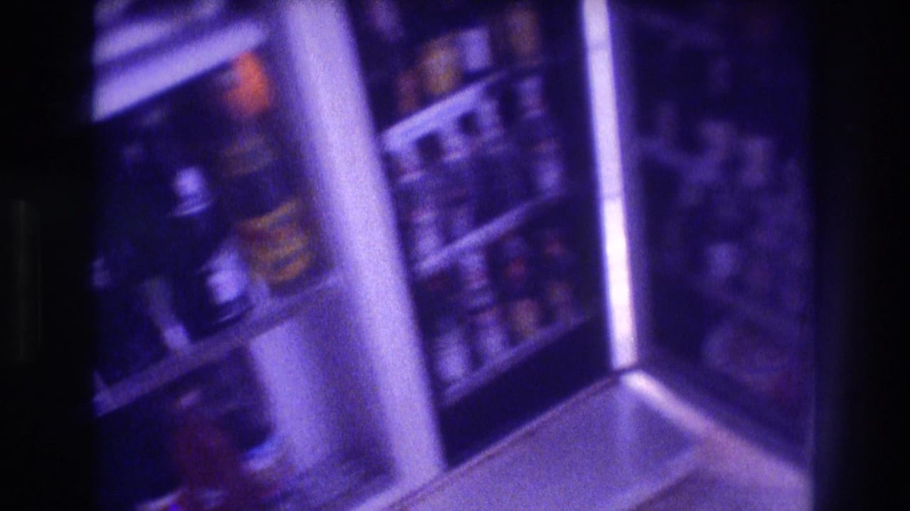 Angled view of a refrigerator interior with shelves of bottles, purple color cast.