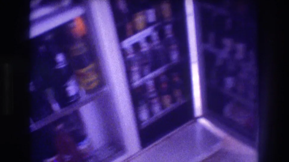 Handheld 8mm shot of a refrigerator interior stocked with bottles, strong purple color cast, Acapulco 1982.