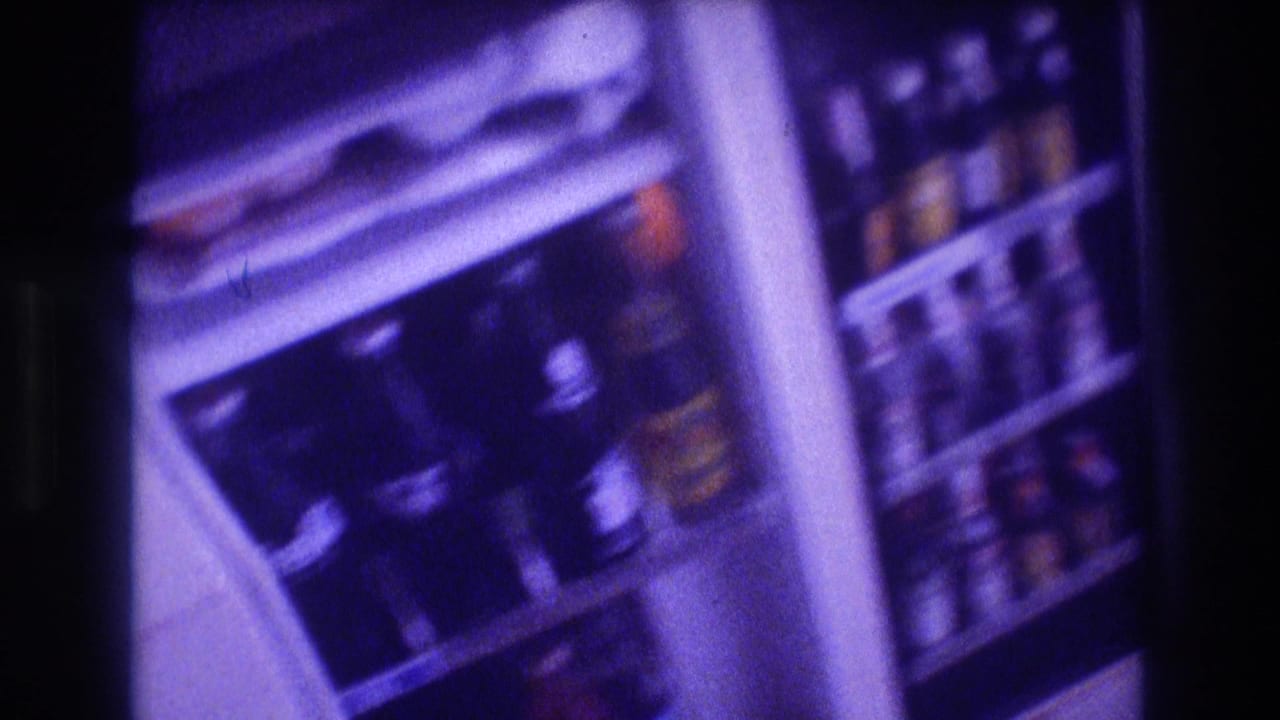 Open refrigerator in 1982 Acapulco home-movie footage with glass soda bottles, door storage, and visible branded labels under a purple film cast.