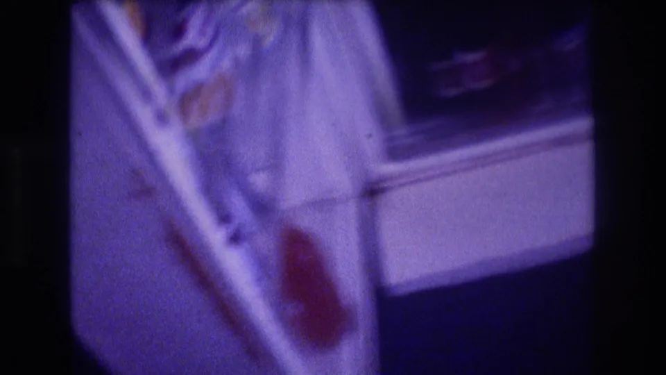 8mm home-movie close-up of open refrigerator interior, circa 1982, showing white door liner, shelving, and a red-labeled item amid pronounced purple film color shift.