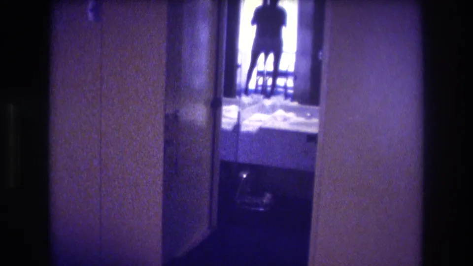 8mm home movie showing a dim interior hallway, tan-brown walls, a backlit adult silhouette in a bright doorway, and items on the floor, Acapulco circa 1982.