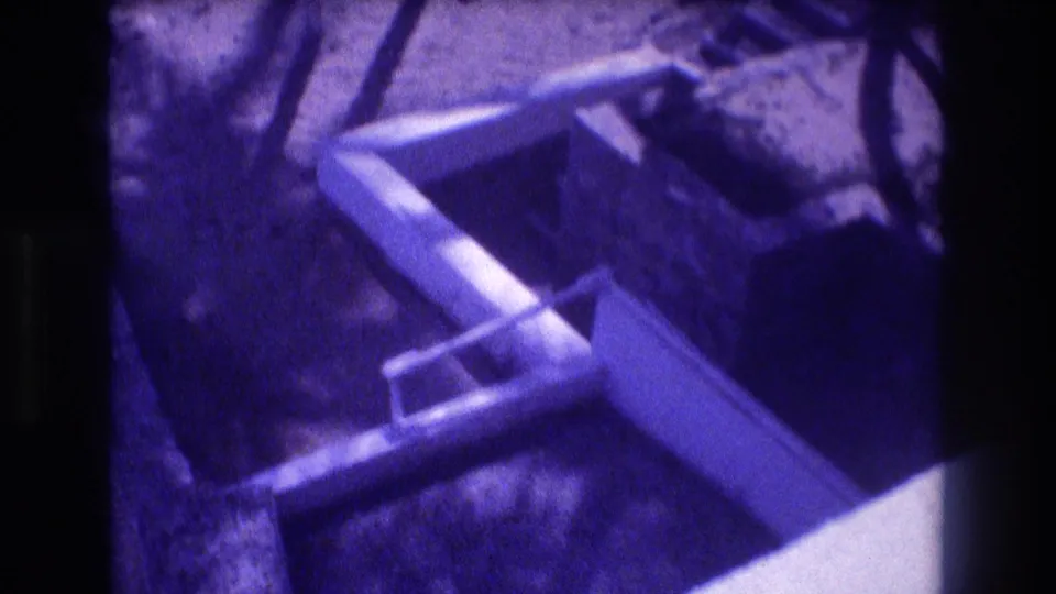 Construction site formwork and what appears to be coiled or circular material on an earthen floor, from a 1982 Acapulco 8mm home movie; pronounced purple dye shift throughout.