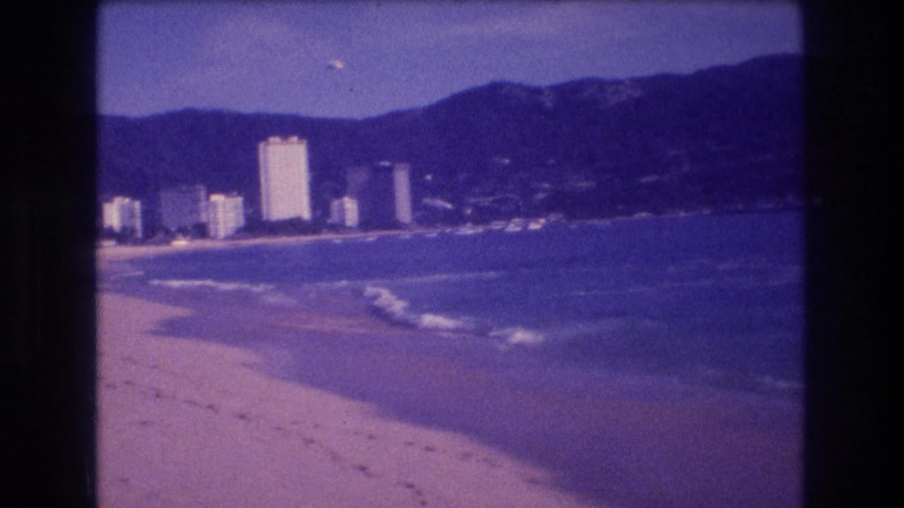 Beach panorama with whitecaps, white hotel towers along the shore, and dark mountains; slightly shifted framing from frame 0.