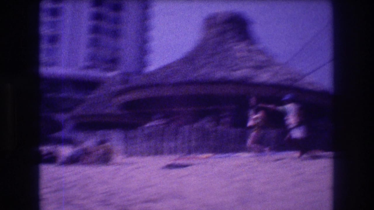 Motion-blurred 8mm frame panning past a large thatched palapa hut in Acapulco, 1982, with a person moving rapidly through frame suggesting the zip-line ride in progress.