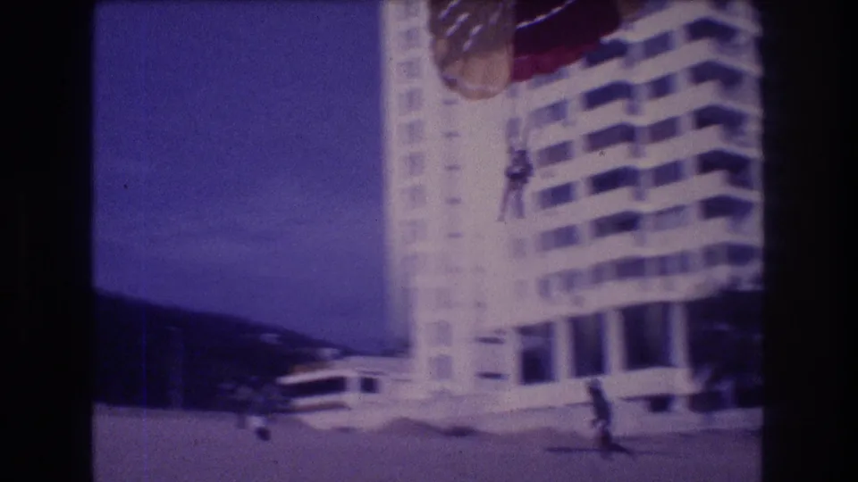 Super 8 home movie, c.1982 Acapulco: parasailor approaching beach landing with a running figure in the foreground, resort hotel behind