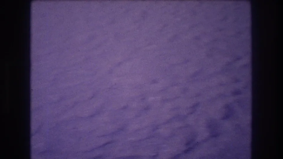 Wide sandy beach with heavy purple color shift and grain; transitional frame from an 8mm home movie shot in Acapulco, Mexico, 1982.