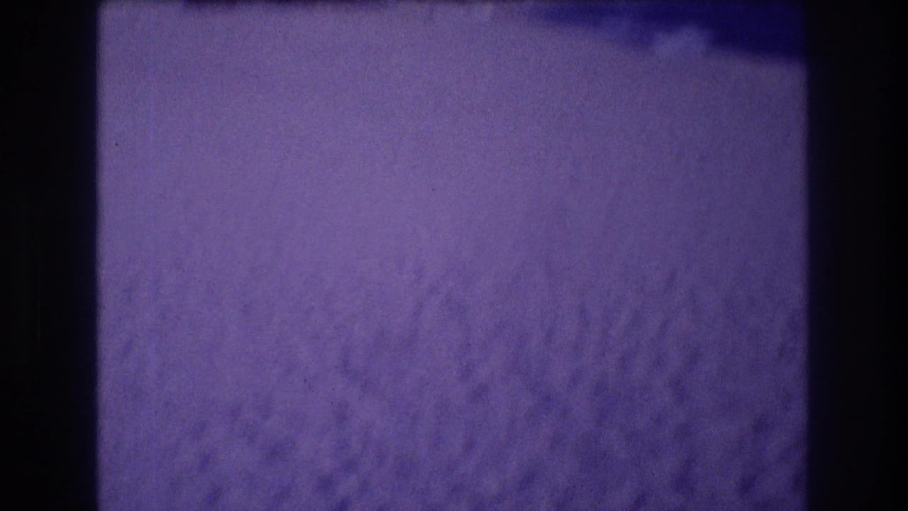 Close-up of wind-rippled sand with a strong purple color cast from aged 8mm film.