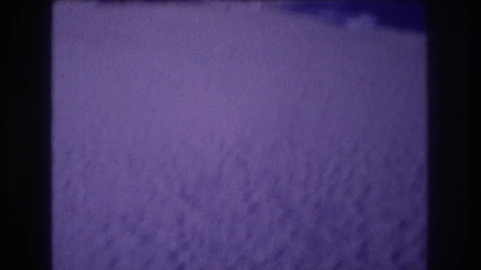 Extreme close-up of beach sand surface, circa 1982 Acapulco Mexico, with heavy violet dye-shift characteristic of aged 8mm film stock.