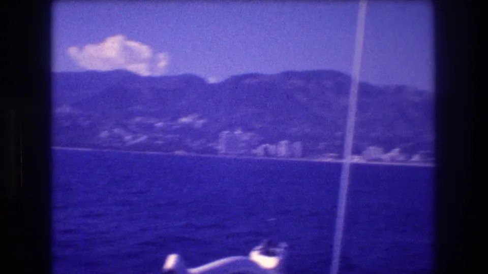 8mm home movie shot from a sailboat in Acapulco bay, 1982 — stay lines cross the foreground while the hotel strip and mountains fill the background